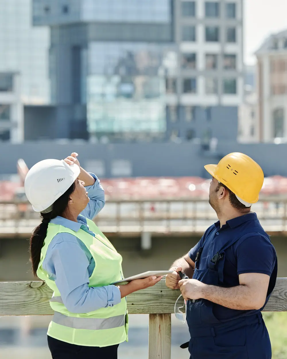 Ingineri care verifică o construcție, orașul în fundal