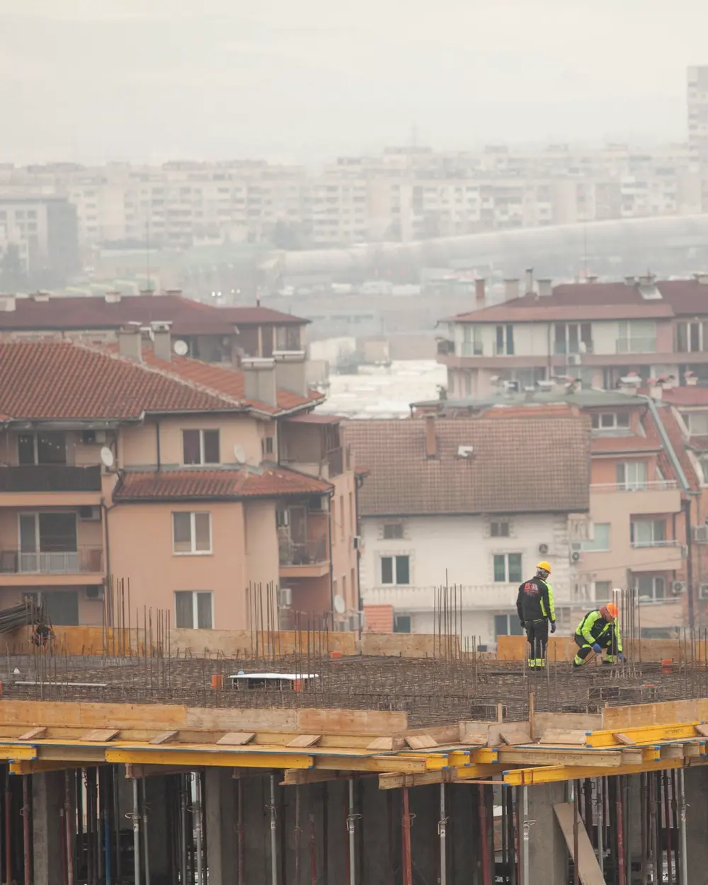 Echipă pe o placă armată, macara, acoperișuri roșii